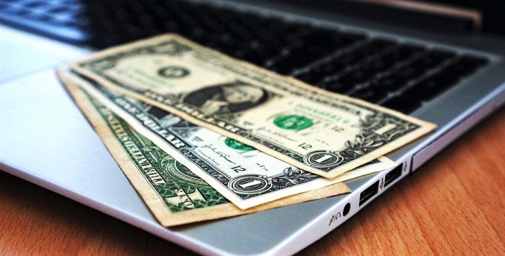 ノートパソコンの上にドル札が載っている画像